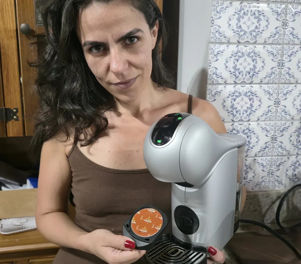 Cecília com uma cápsula NESCAFÉ Dolce Gusto na mão, ao lado da Genio S Touch
