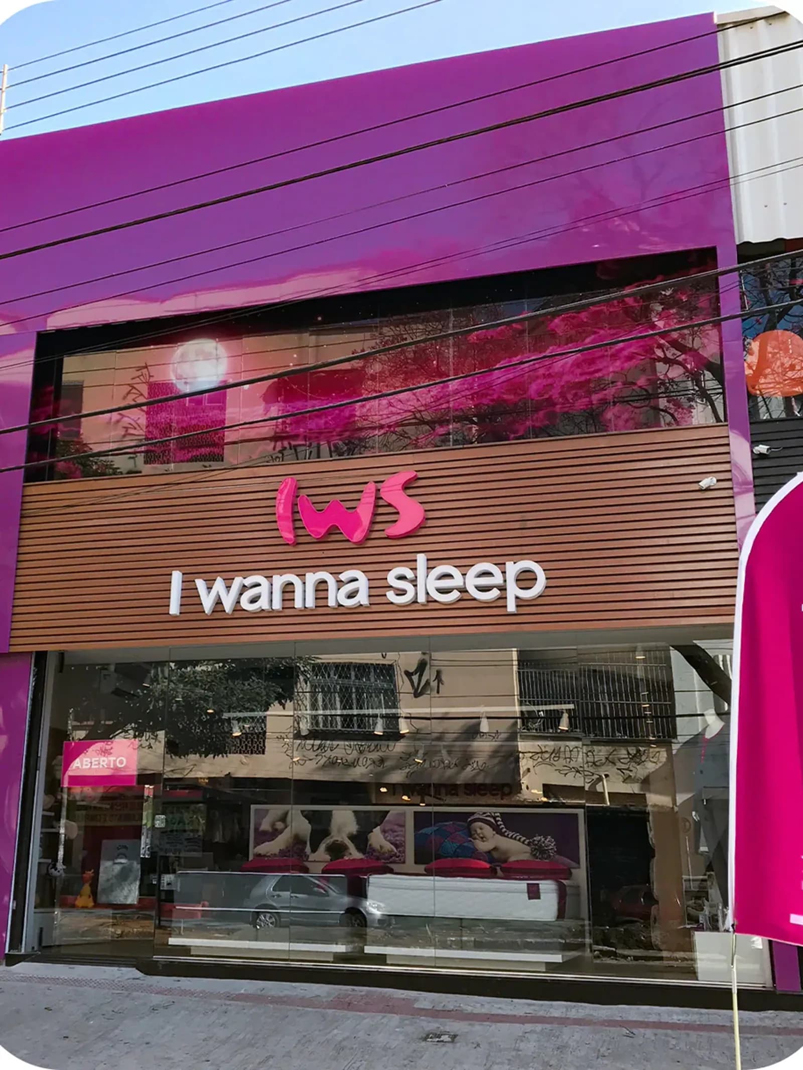 Fachada de outra loja da I Wanna Sleep, com letreiro 'IWS I wanna sleep' e colchão em exposição na vitrine