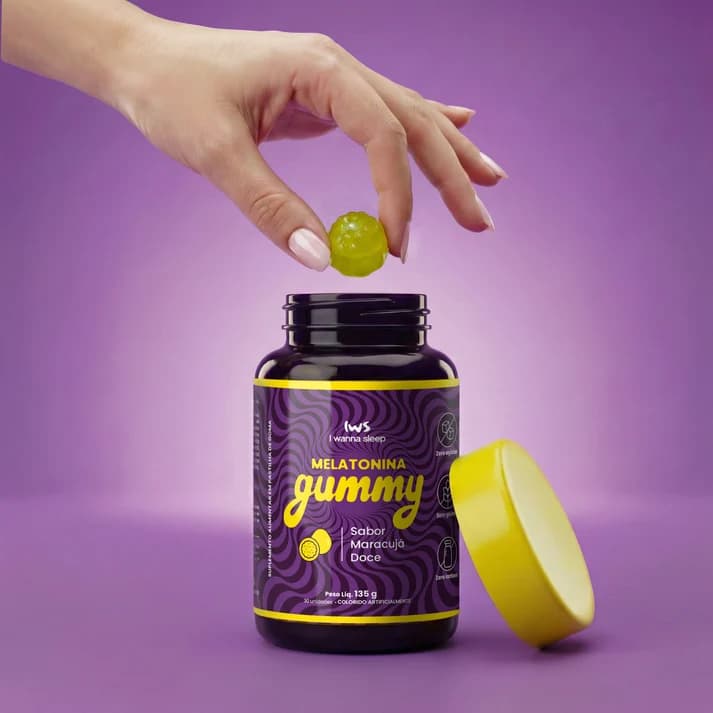 Mão colocando uma goma no pote de Melatonina Gummy IWS