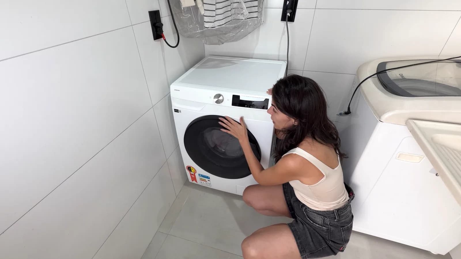 Cecília ao lado da lava e seca Samsung 13 kg branca recém-instalada na lavanderia