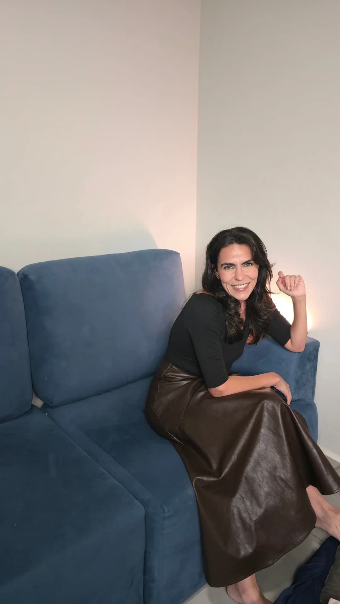 Cecília sentada no sofá modular DAMIE azul, na sala de casa
