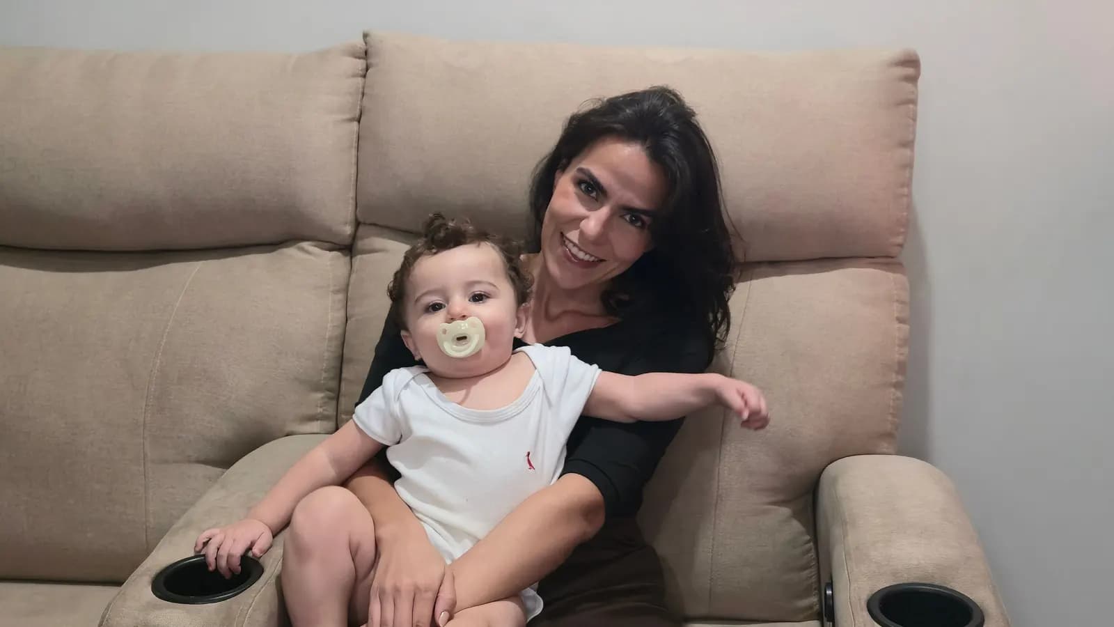 Cecília Mauad com o Ian no colo na poltrona reclinável DAMIE bege, com porta-copos nos braços