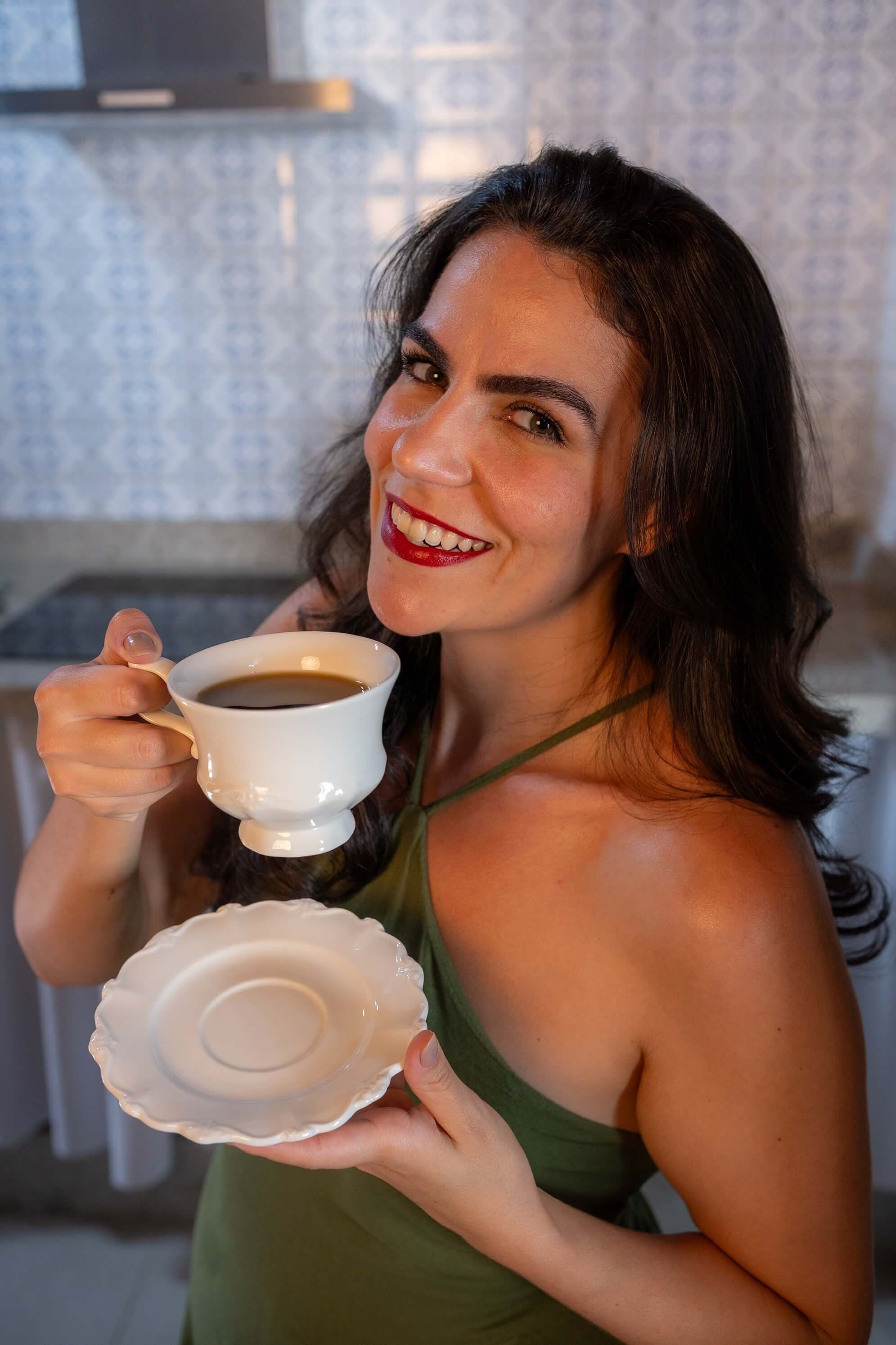 Cecília holding a cup of coffee in her kitchen