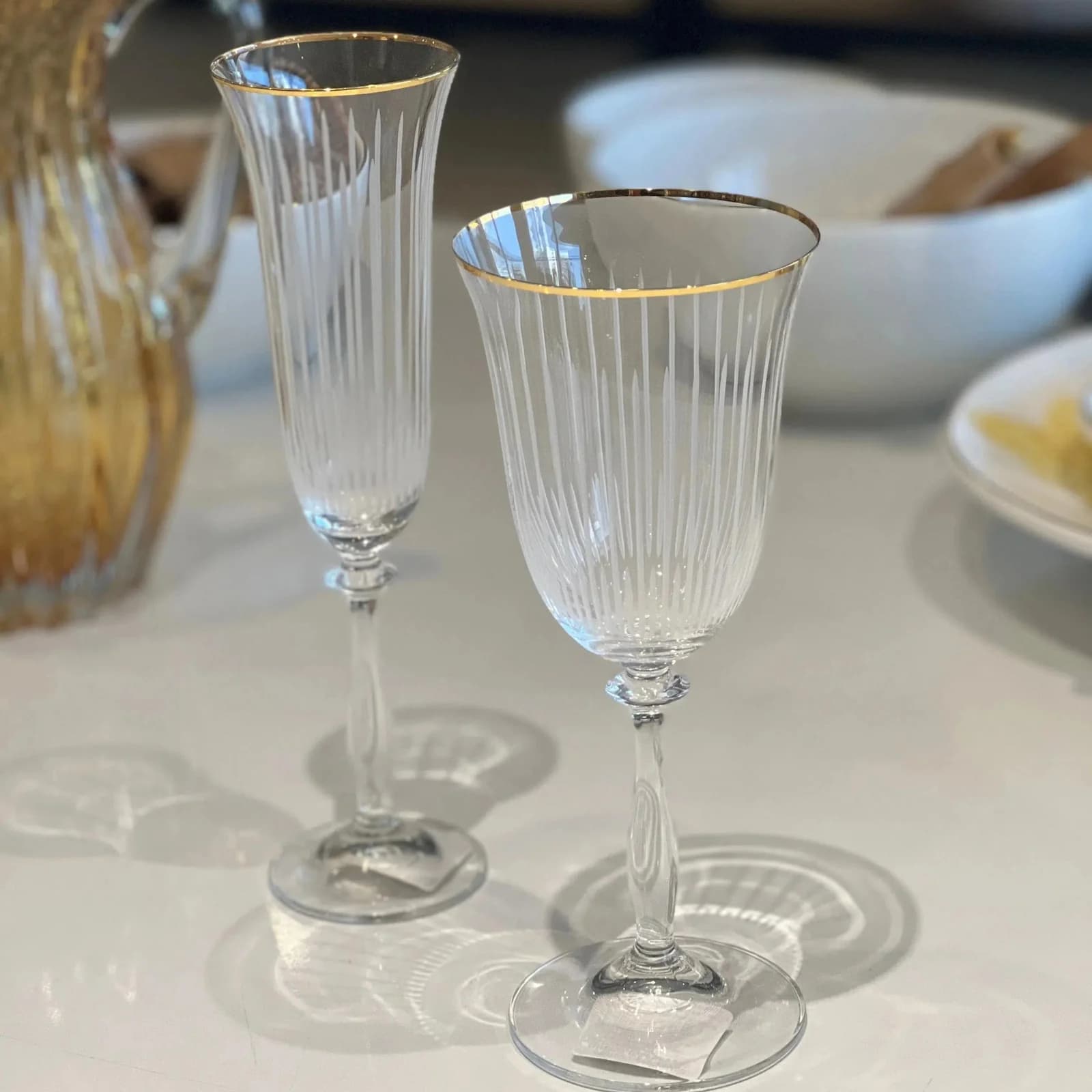 Duas taças de cristal Bohemia Angela com borda dourada sobre uma mesa clara
